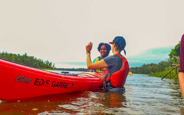 an instructor gives direction to a student in a kayak on an outward bound trip